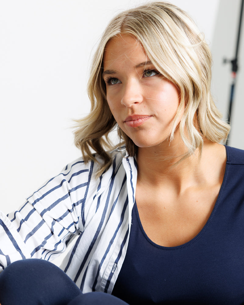 Woman with blonde hair wearing a blue top and striped scarf.