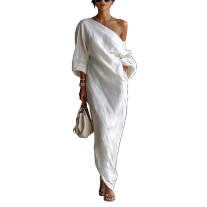 White off-shoulder linen dress showing relaxed fit and asymmetrical hemline detail