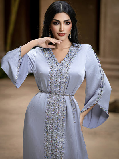 Woman wearing a light blue dress with intricate beadwork.
