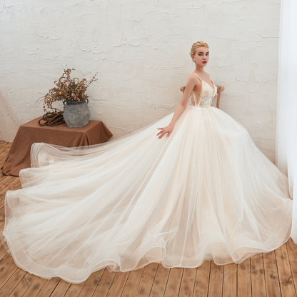 Woman in a white wedding dress standing in a room with a white brick wall and wooden floor.