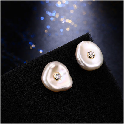 Pearl earrings with embedded diamonds on a black stand against a dark background