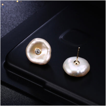 Pearl earrings with a central gemstone on a black surface