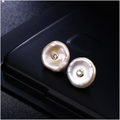Pearl earrings with embedded diamonds on a black surface