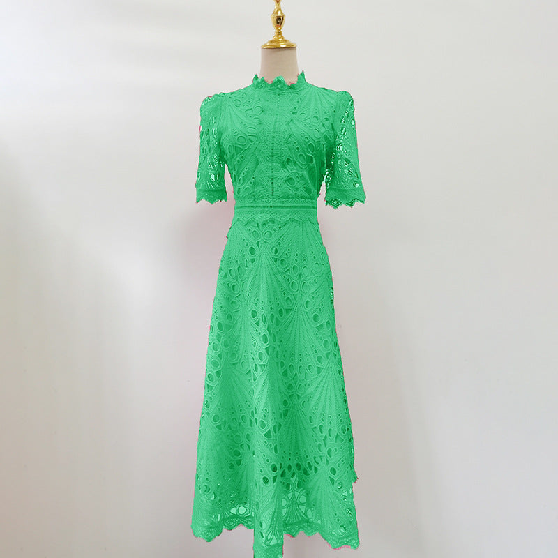 Woman wearing a green short sleeve lace embroidered A-line dress with cinched waist
