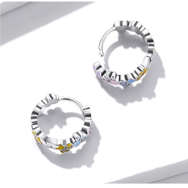 Silver hoop earrings with floral designs on a white background
