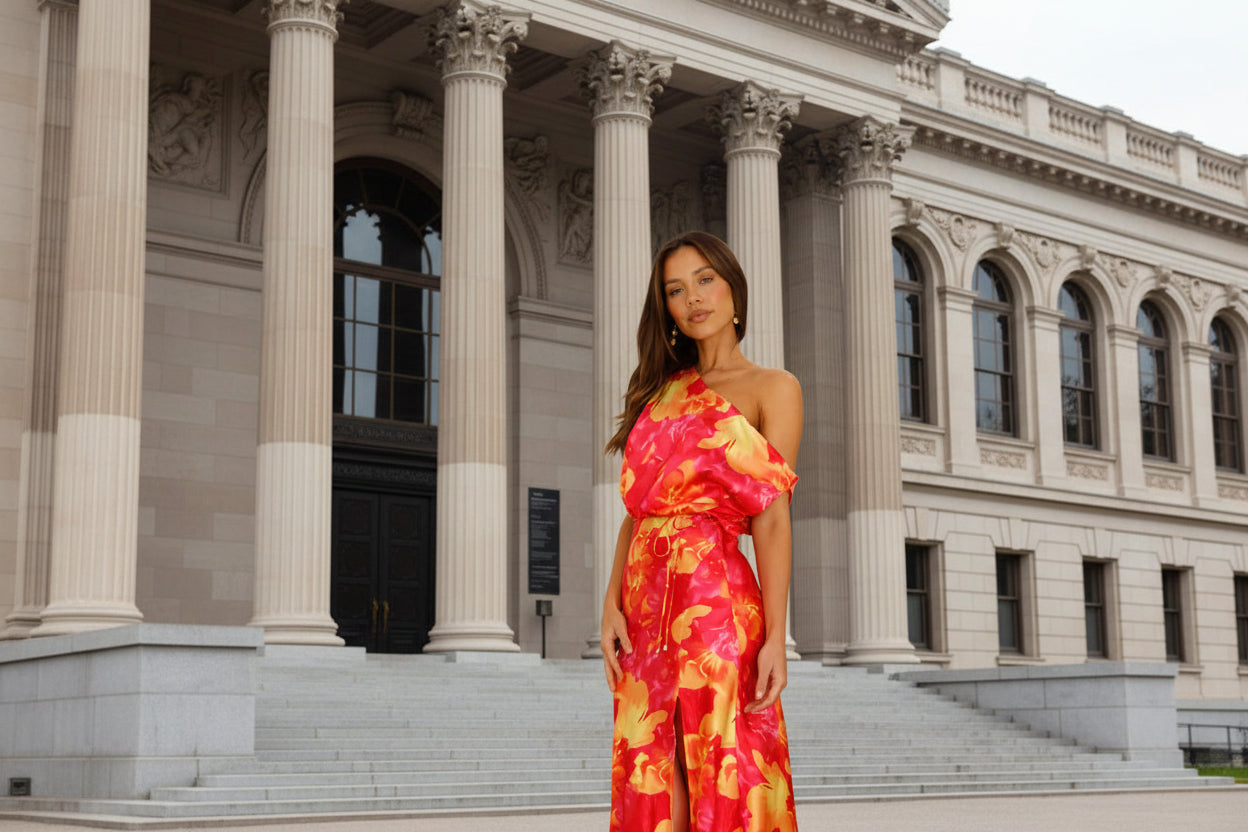 Woman wearing a vibrant red and orange floral one-shoulder dress 