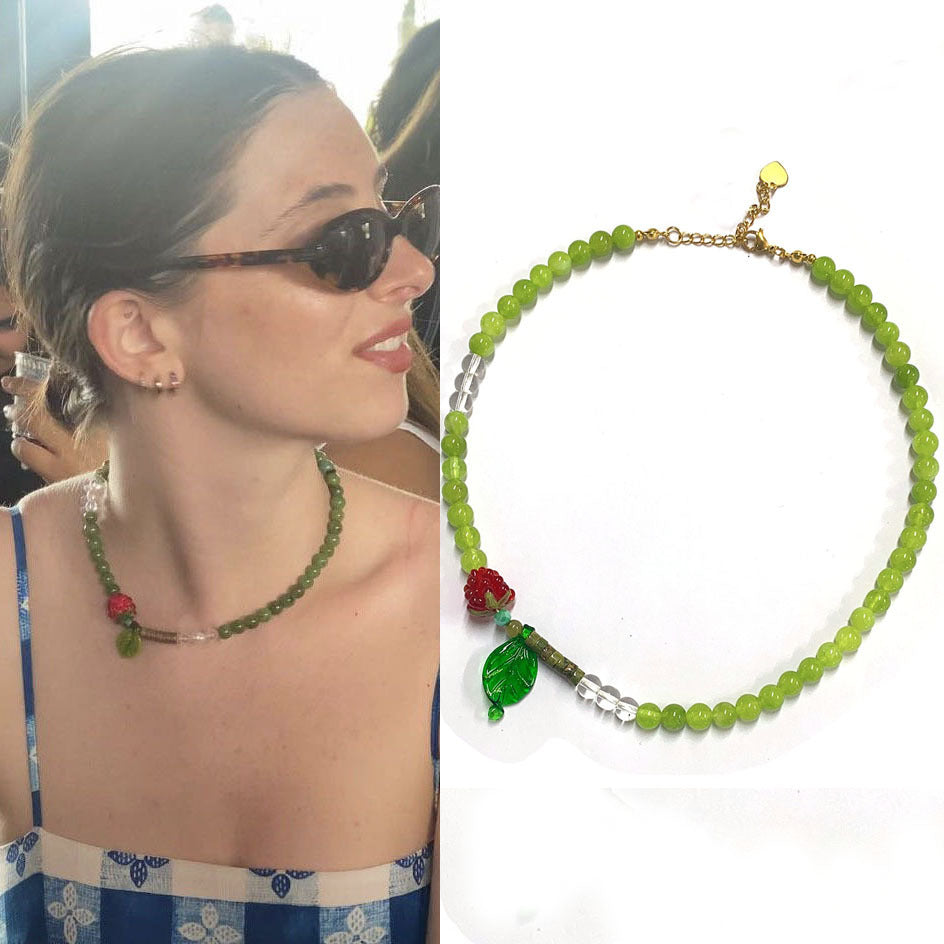 Woman wearing a green beaded necklace with red accents