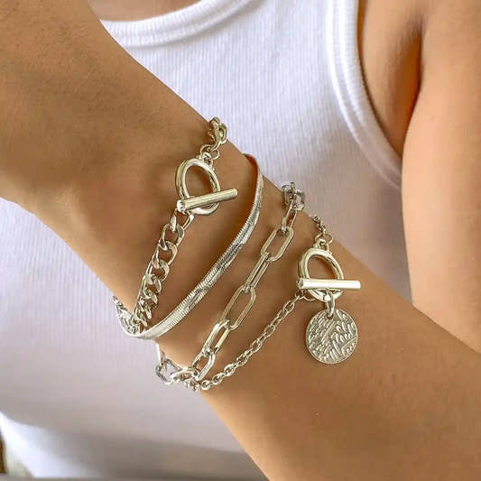 Silver chain bracelets on a wrist with a plain background