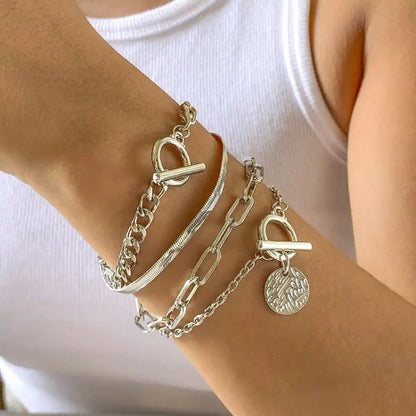 Silver chain bracelets on a wrist with a plain background