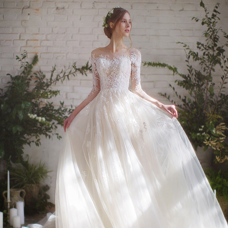 Front view of ivory A-line bridal gown with sweeping cathedral train and sheer lace sleeves

