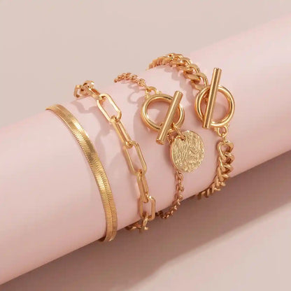 Gold bracelets on a wrist against a beige background