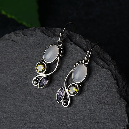 Silver earrings with gemstones on a dark stone surface