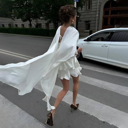 White High-Gloss Satin Mini Dress with Layered Ruffle Skirt and Trailing Cape Panels
