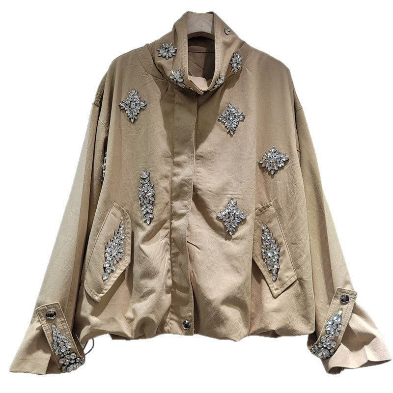 A beige long-sleeve jacket with silver rhinestone embellishments, featuring a high stand collar, front button closure, and large front flap pockets.