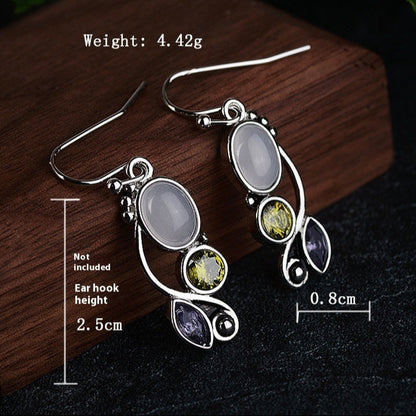 Silver earrings with gemstones on a dark surface, accompanied by measurements and product details.