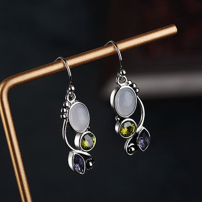 Pair of silver earrings with gemstones on a dark background