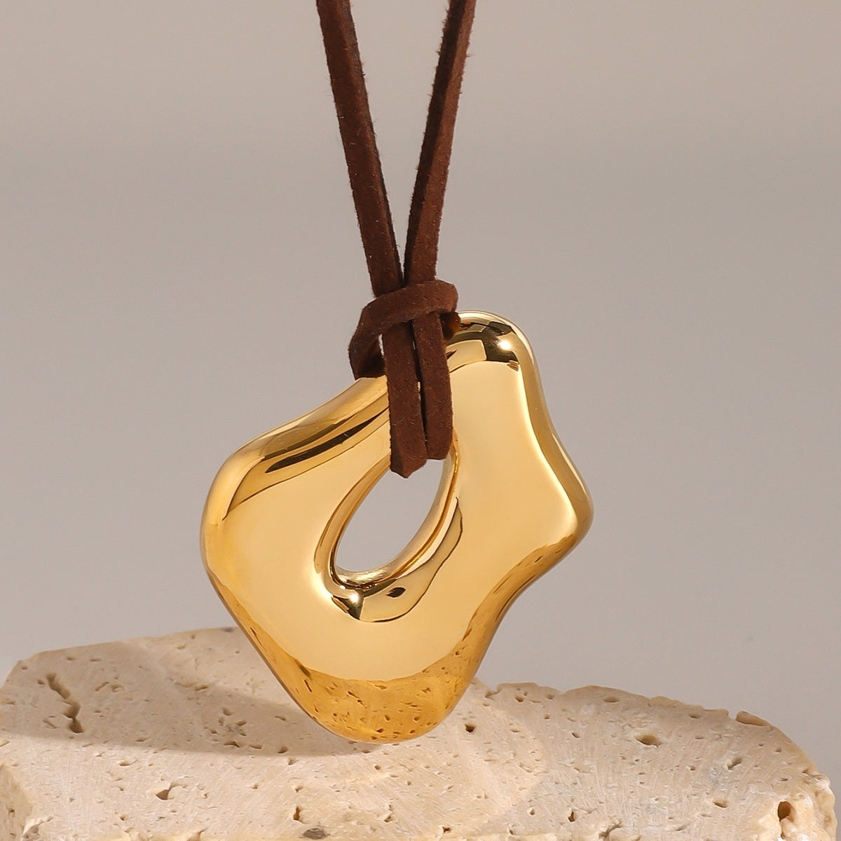 Gold pendant on a brown leather cord 
