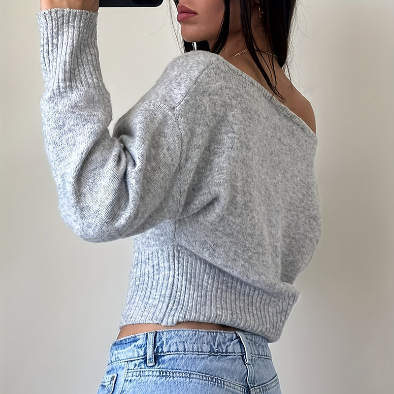 Person wearing a gray ribbed  cotton sweater and blue jeans 