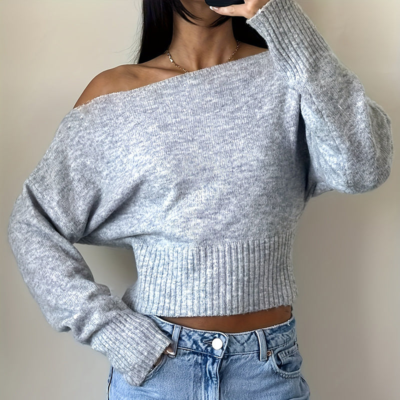 Person wearing a gray off-shoulder sweater and blue jeans 