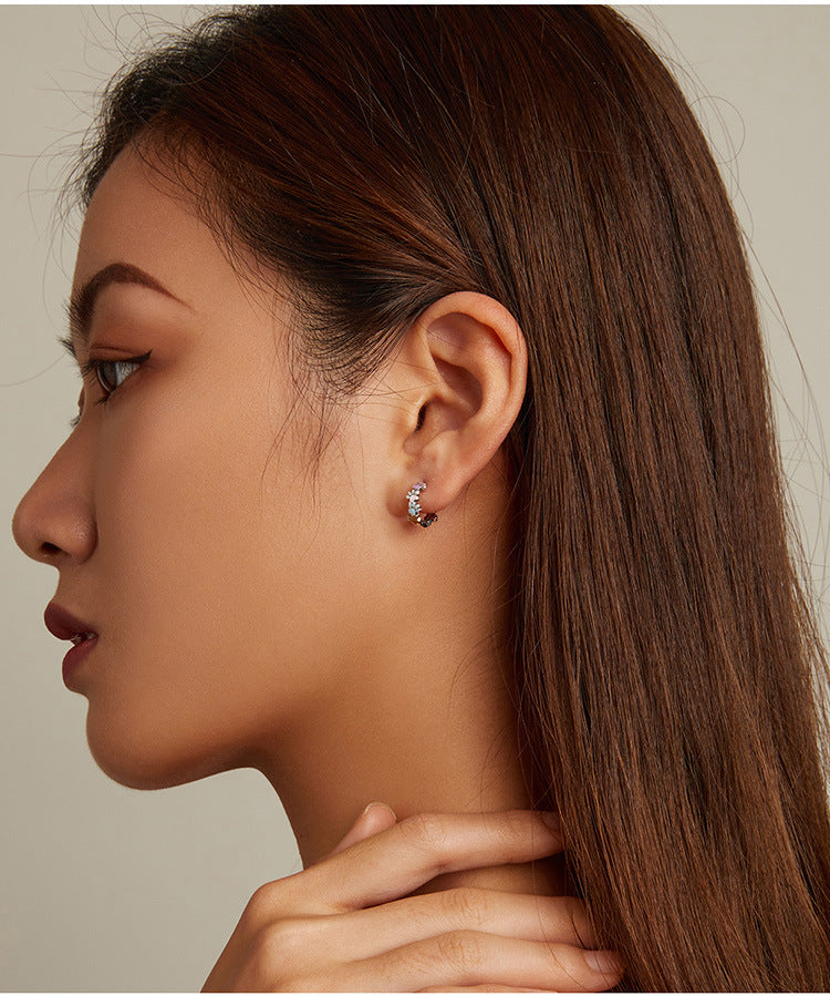 Close-up of a woman wearing a diamond earring on a neutral background