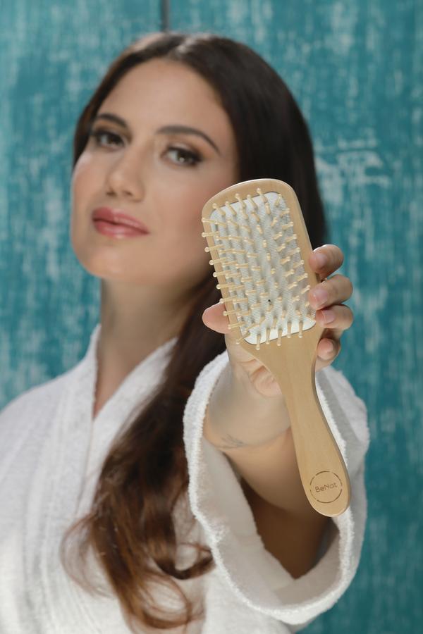 Woman holding a wooden hairbrush made from bamboo, eco friendly 