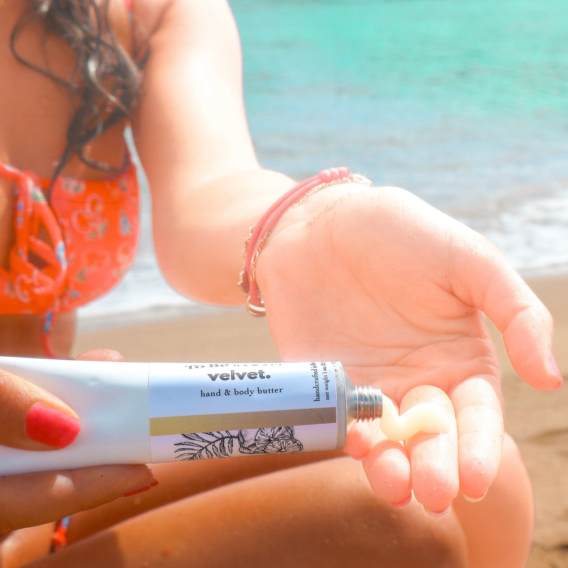 Person applying velvet hand & body butter on a beach