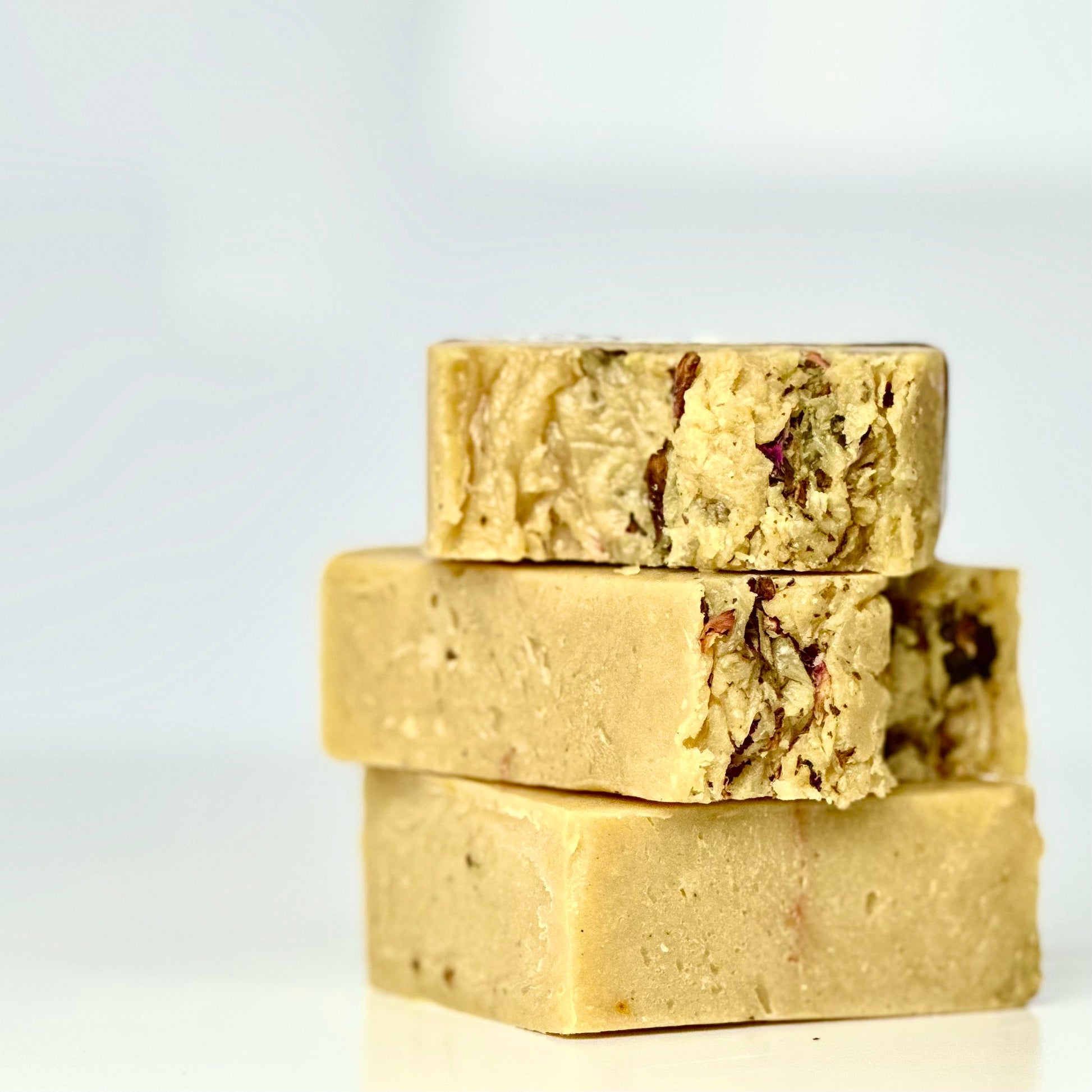 Three stacked organic soap bars with visible ingredients for sensitive skin