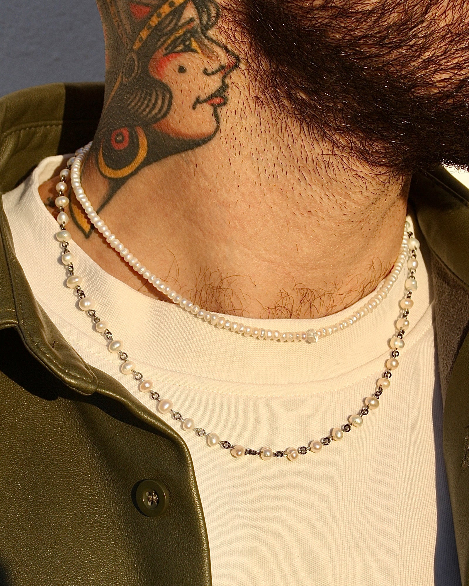 Person wearing a necklace with a tattoo on their neck