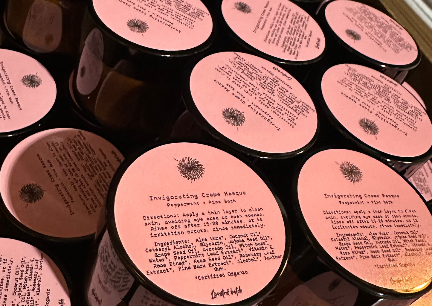 Multiple containers with pink labels and text on a reflective surface