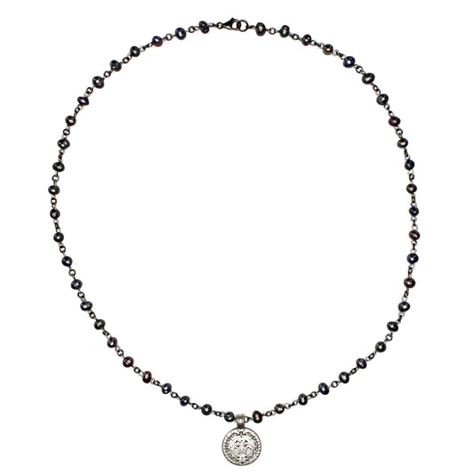 Necklace with black beads and a silver pendant on a white background