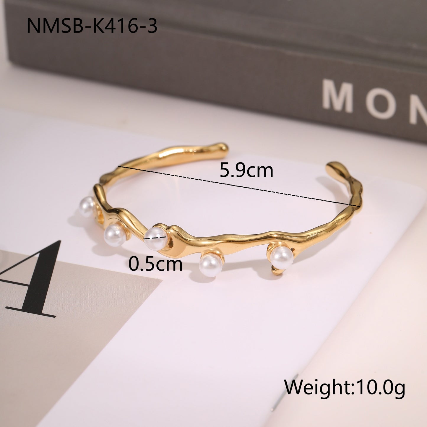 Gold bracelet with pearls on a white surface, 