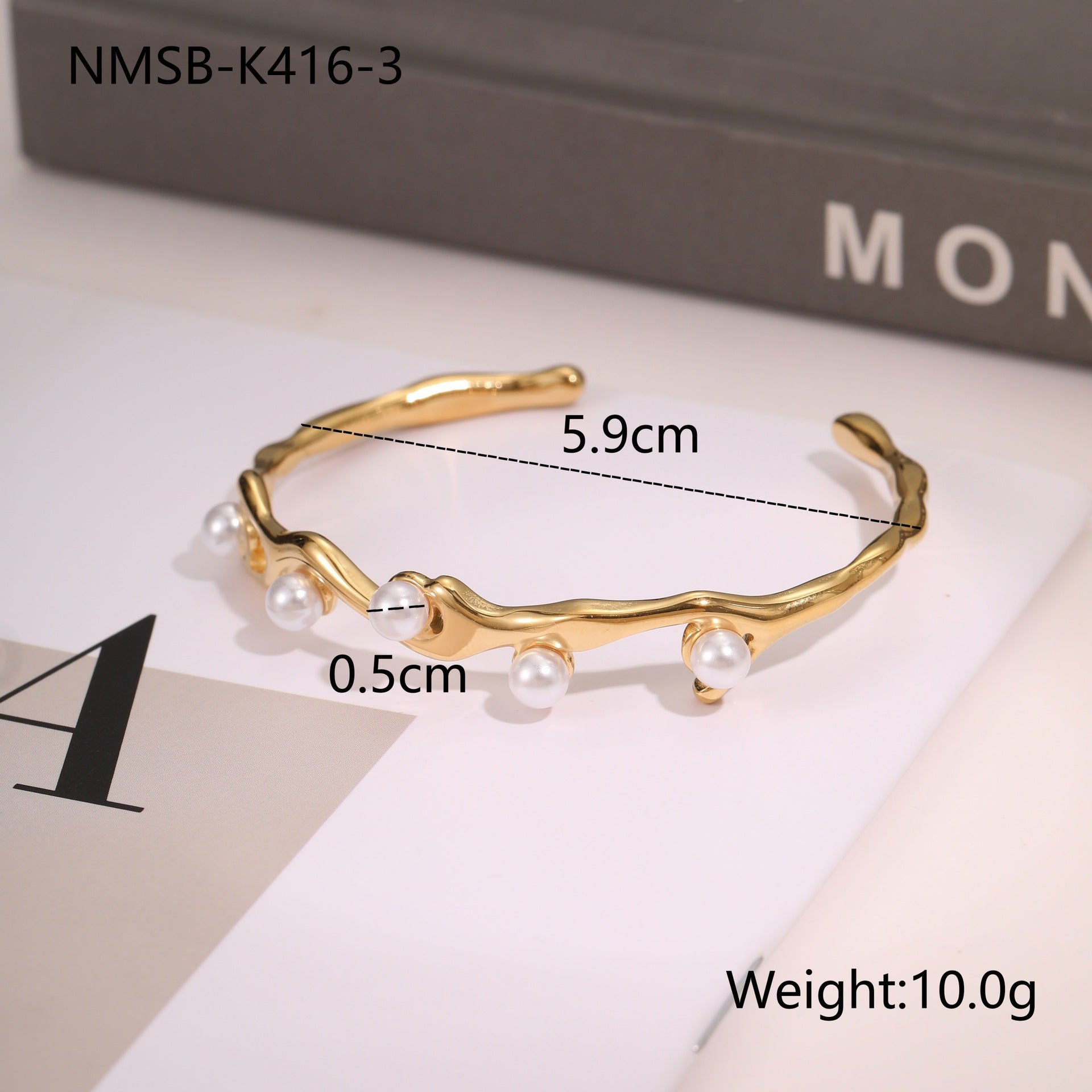 Gold bracelet with pearls on a white surface, 