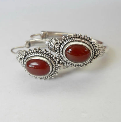Silver bracelet with red stones on a white background