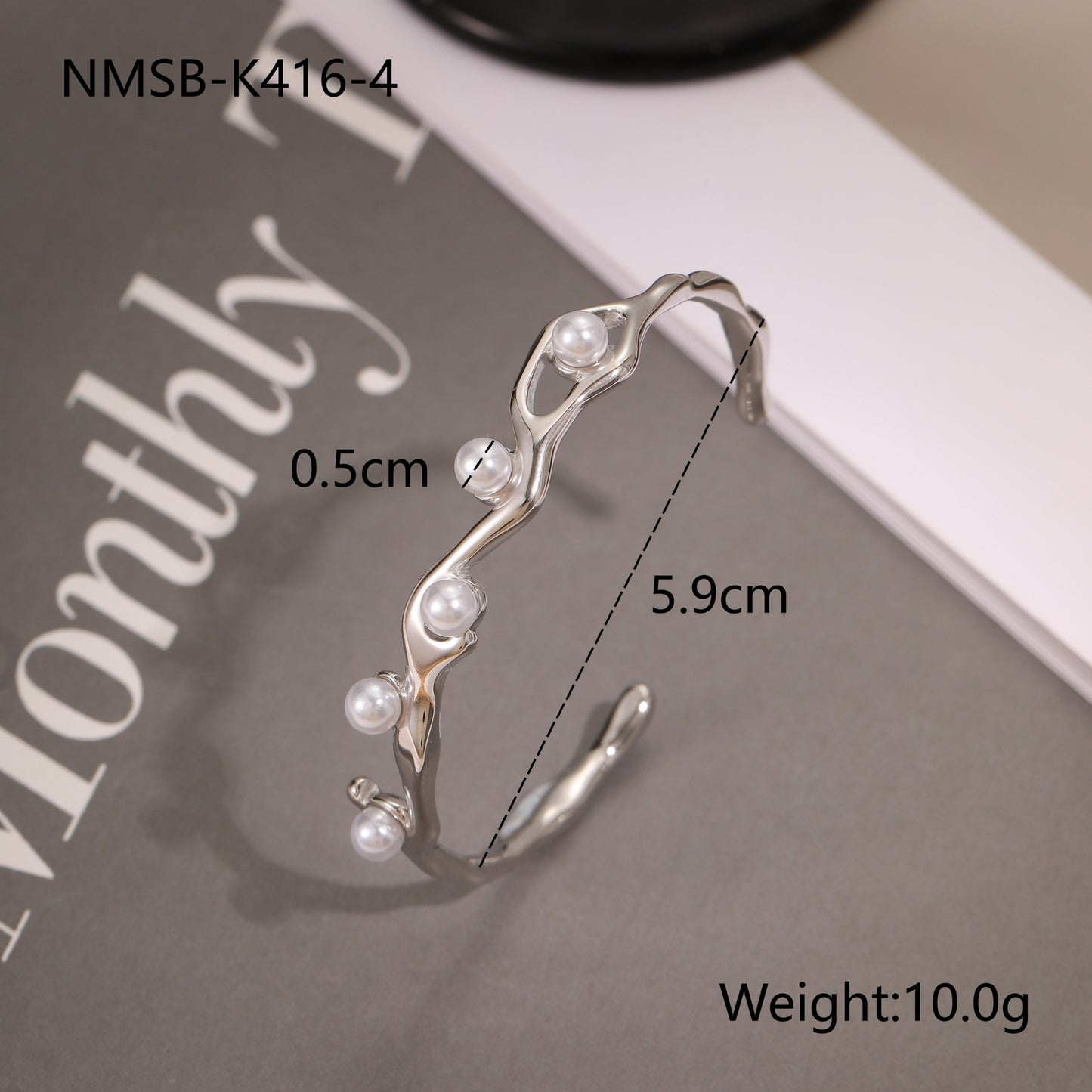 Silver bracelet with pearls on a magazine background, 
