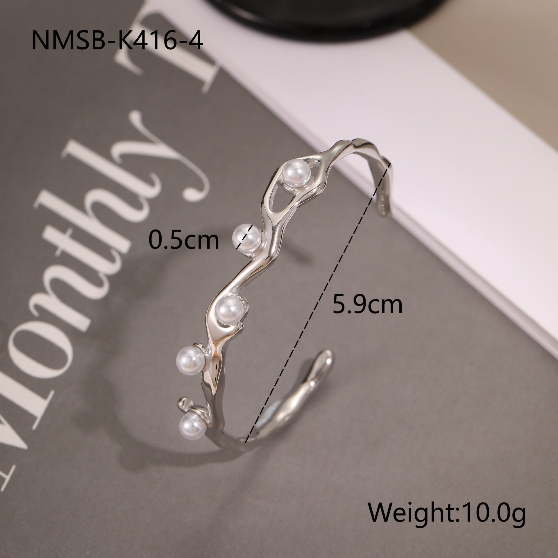 Silver bracelet with pearls on a magazine background, 