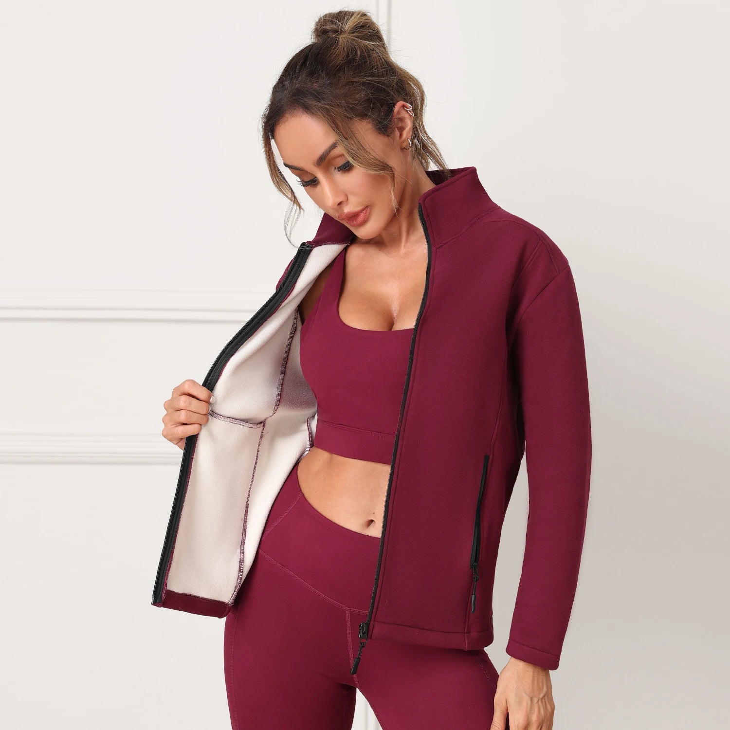 Woman wearing a burgundy athletic outfit with a jacket 