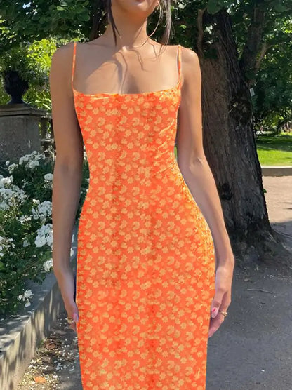 Woman wearing an orange floral dress standing outdoors with greenery in the background