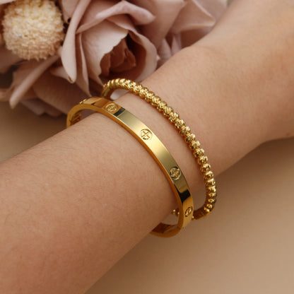 Close-up of zircon stones on gold bangle – bezel setting on high-polished stainless steel
