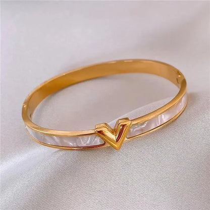 Gold V-shape bangle bracelet with shell inlay on white surface – elegant women's gift jewelry
