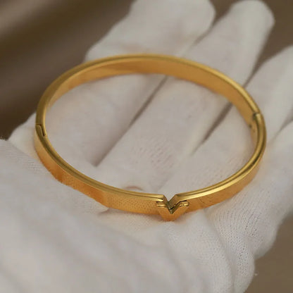 Sleek gold bangle with architectural V detail on white fabric – tarnish-resistant luxury bracelet
