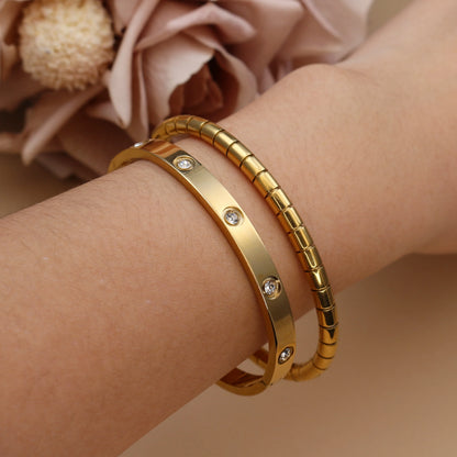 Stacked gold bangles on wrist – smooth and ribbed stainless steel bracelet set
