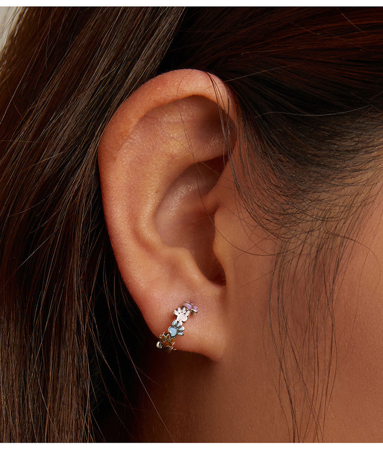 Close-up of an ear wearing a delicate earring with small stones.