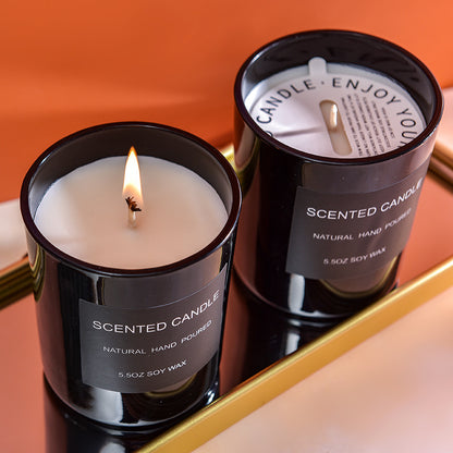 Two scented candles in black containers with labels 