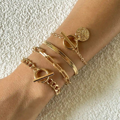 Gold bracelets on a wrist against a textured beige background