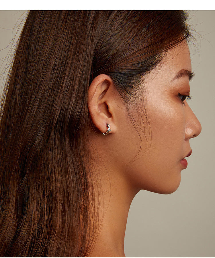 Close-up of a woman wearing a diamond earring on a neutral background