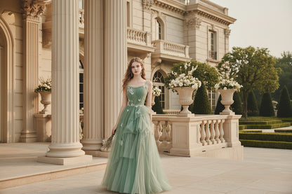 Woman wearing a sage green glitter tulle A-line evening gown with butterfly appliqués and floral lace waist

