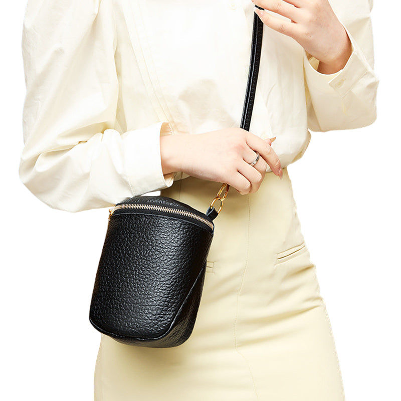 Beige cylindrical satchel displaying natural texture and brass-tone details

