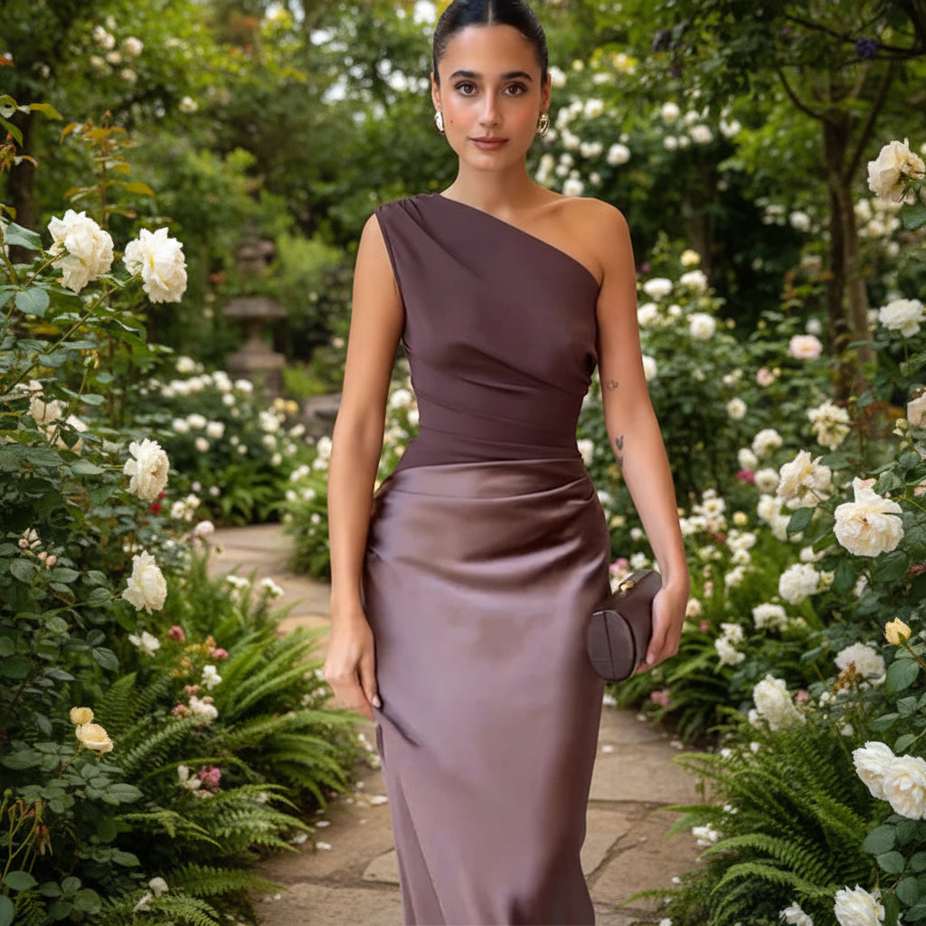 Woman in a one-shoulder brown dress holding a clutch 
