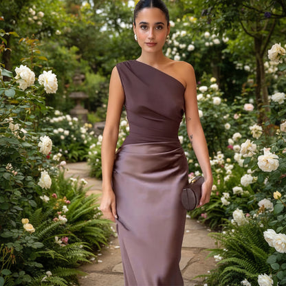 Woman in a one-shoulder brown dress holding a clutch 
