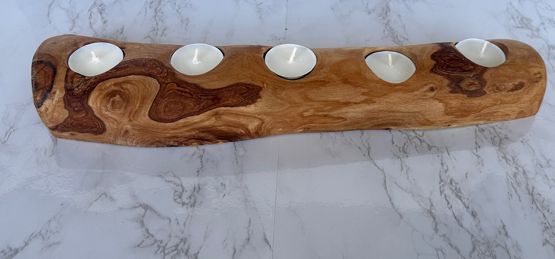 Wooden candle holder with five candles on a marble surface